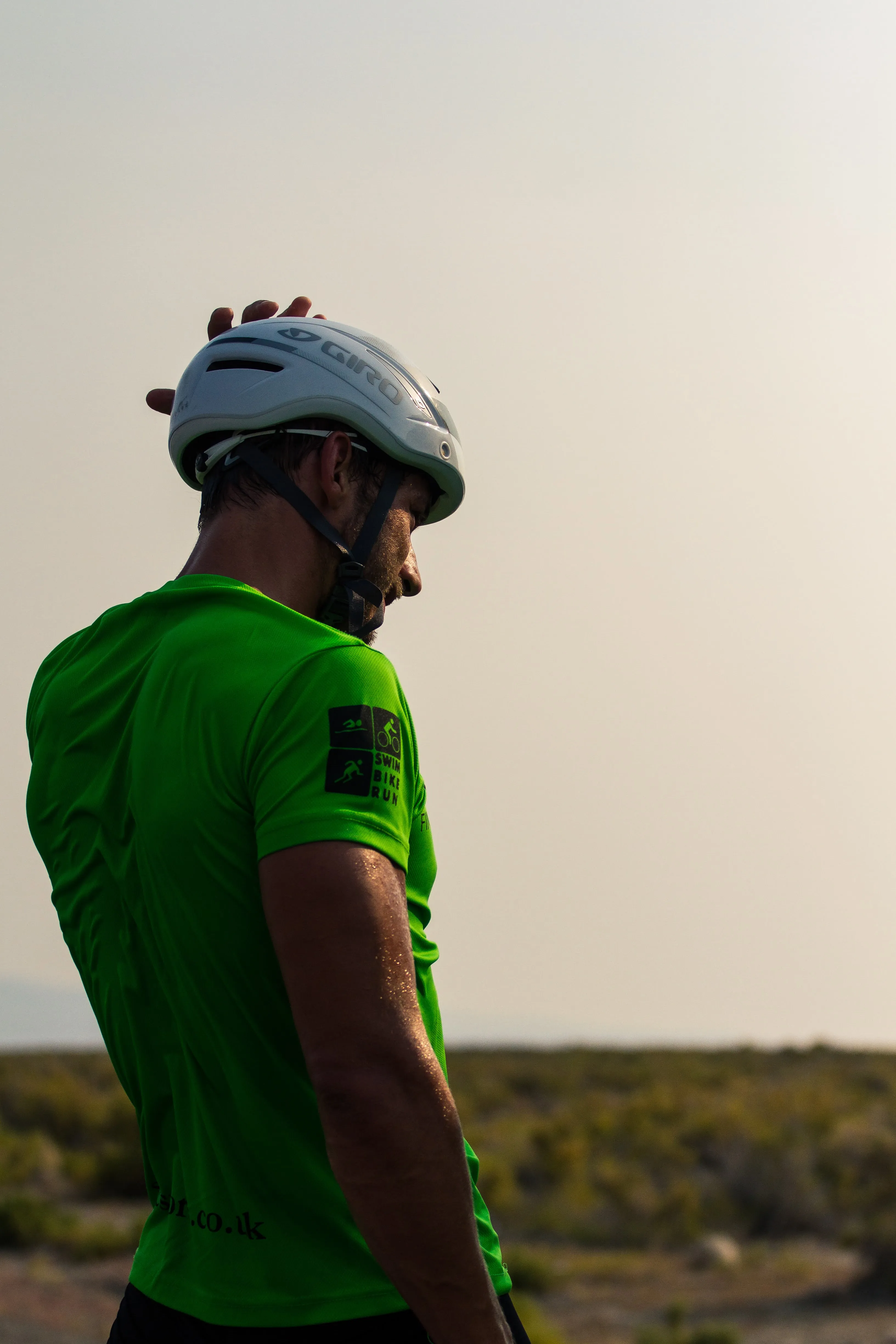 Profile portrait of a rider in a helmet, backlit by a hazy sky