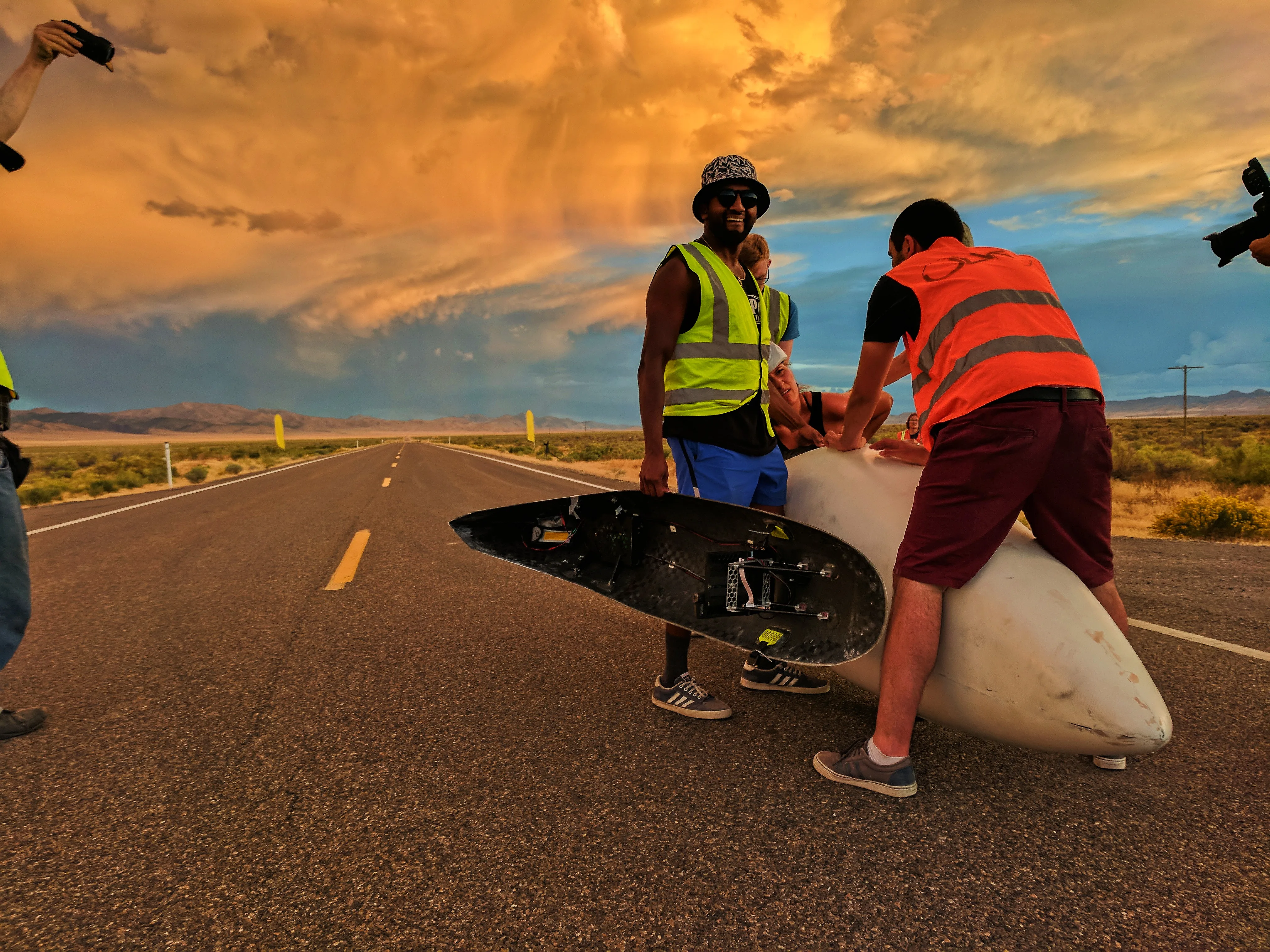 The team fitting the ARION3 fairing on the road under a dramatic orange and blue storm sky